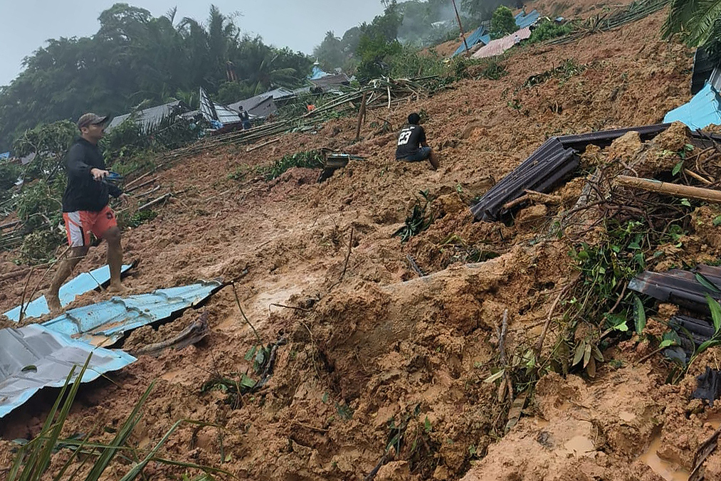 Seorang warga berjalan di lokasi kejadian tanah longsor di Kecamatan Serasan, Kabupaten Natuna, Kepulauan Riau, Senin (06/03).