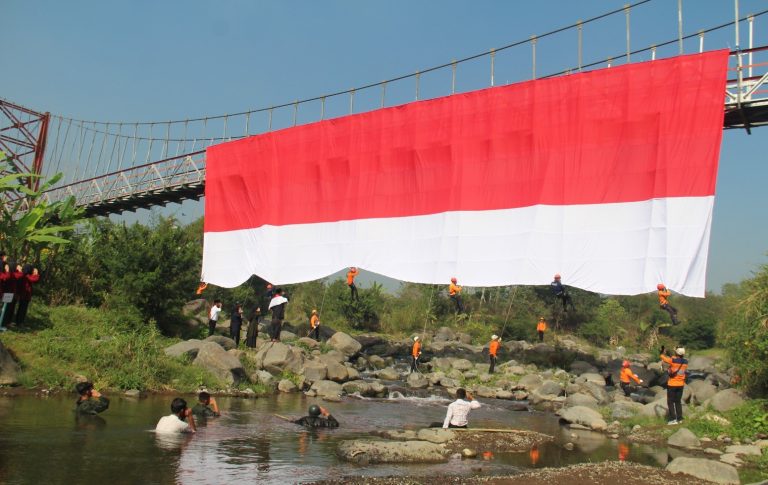 Kolaborasi SMK MIPHA, BPBD dan FPTI Bentangkan Bendera Merah Putih di Jembatan Gantung